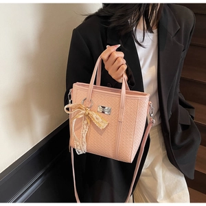 Close-up of pink woven bucket bag with elegant lace bow and metallic logo plaque