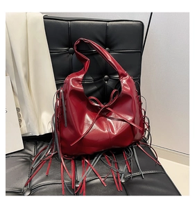 Close-up of a dark red PU leather crescent tote bag with fringe and bow detailing