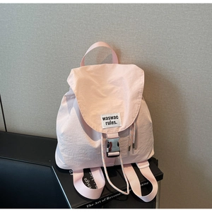 Detail of light pink waterproof nylon backpack featuring metal buckle and drawstring closure