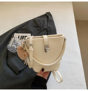 Détail du sac seau crème avec boucle argentée et charmant pendentif ours en peluche