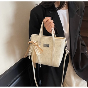 Detail of cream crocodile embossed bucket bag with lace bow charm and silver logo
