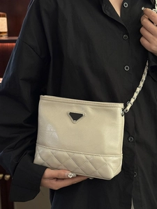 Chic cream quilted bucket bag with silver chain strap shown as a crossbody on a model