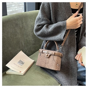 Detail of vintage brown PU leather handbag with unique pocket stitching and belt accent