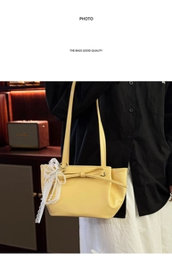 Détail d'un sac bandoulière jaune vif avec nœud papillon et pendentif perle dentelle