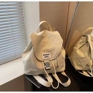 Detail view of cream nylon backpack with flap closure and stylish drawstring opening