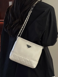 Quilted beige bucket bag with silver chain strap and metal logo on a model