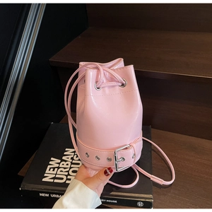 Détail d'un sac seau rose vif avec cordon de serrage et boucle de ceinture argentée