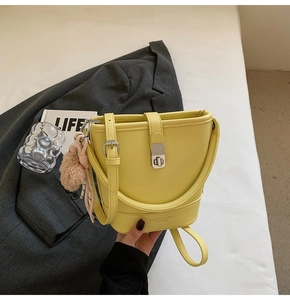 Sac seau jaune en cuir grainé avec pompon en fourrure et fermoir rotatif argenté