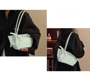 Détail du sac seau vert menthe avec nœud en dentelle blanche et pompons de perles élégants