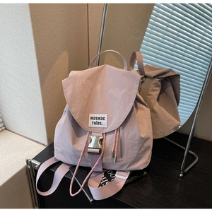 Detail of light pink canvas backpack showing drawstring closure and silver metal buckle