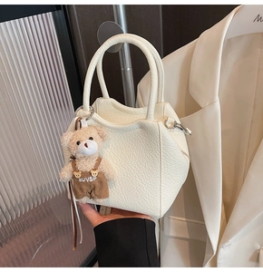 Detalle del bolso tote blanco crema con textura de lichi y colgante de osito
