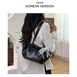 Détail du sac à bandoulière plissé noir avec nœud en dentelle et perles sur modèle