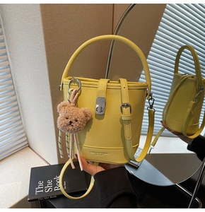 Détail du sac seau jaune en cuir grainé avec fermoir argenté et breloque ours