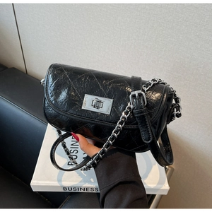 Detailed view of black quilted chain bag with silver twist lock and glossy leather finish