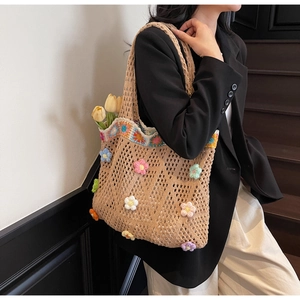 Dettaglio di una borsa tote beige all'uncinetto con motivi floreali 3D e manici intrecciati