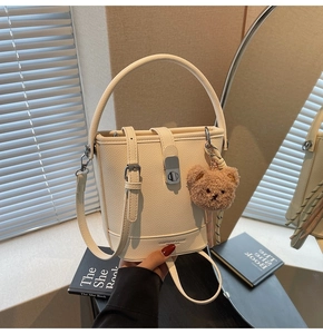 Détail du sac seau en cuir blanc crème avec fermoir rotatif argenté et charm d'ours