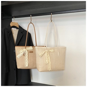 Détail de sacs fourre-tout en paille avec nœuds en dentelle et longues anses en cuir