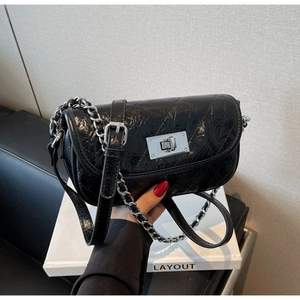 Detail of glossy black quilted leather mini bag with silver chain and twist lock