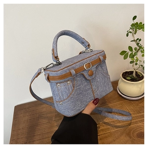 Close-up of mini denim box bag with leather belt detail and detachable shoulder strap