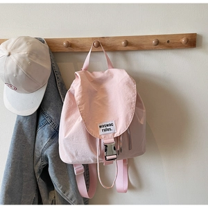 Detail of pink canvas backpack with silver buckle and white label on a wall hook