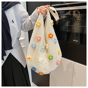 Detail of handmade crochet tote bag featuring 3D floral appliques and knit texture
