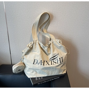 Nahaufnahme der beigen Beuteltasche mit Logo-Detail und passendem runden Münzfach