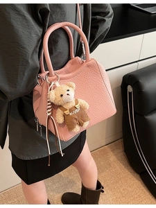 Bolso tipo cubo rosa con textura de lichi y colgante de oso en un entorno de estilo de vida