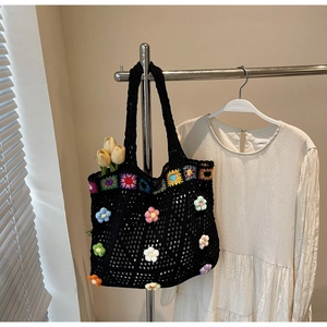 Dettaglio di borsa tote in maglia nera con fiori colorati all'uncinetto 3D fatti a mano