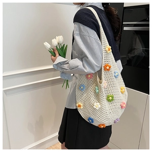 Close-up of a white crochet tote bag with colorful 3D knitted flowers and openwork design