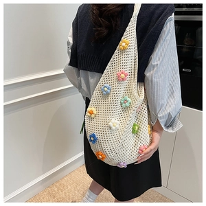 Macro detail of hand-woven crochet tote bag featuring 3D colorful floral appliques