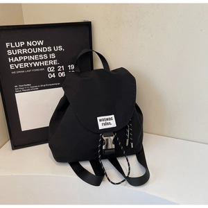 Detail of black canvas backpack with metal buckle closure and stylish woven label