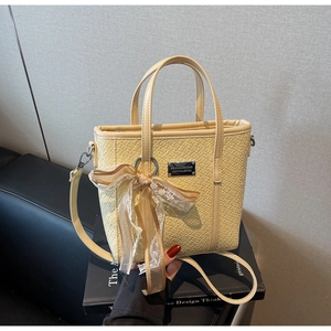 Dettaglio della borsa a secchiello giallo tenue con trama intrecciata e fiocco in pizzo