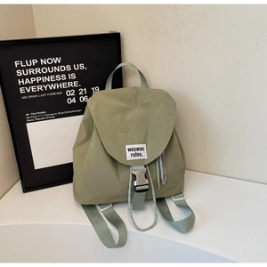 Detail of dust green nylon backpack with snap buckle closure and logo label