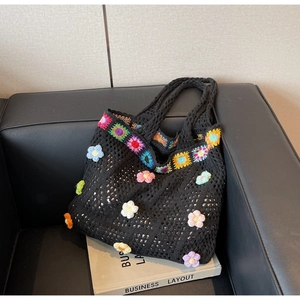Dettaglio ravvicinato di una borsa tote in maglia nera con fiori colorati all'uncinetto 3D