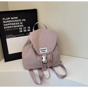 Side view of a mauve canvas backpack with flap buckle and zip pocket on display