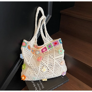 Dettaglio della borsa tote all'uncinetto bianca con ricami floreali boho e trama a maglia