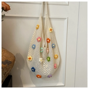 Detailed macro view of colorful handmade crochet flowers on a beige hollow mesh tote bag