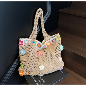 Dettaglio di borsa tote lavorata all'uncinetto con fiori 3D e trama a rete intrecciata