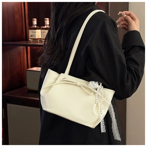 Détail du sac bandoulière plissé crème avec nœud et breloques en perles porté