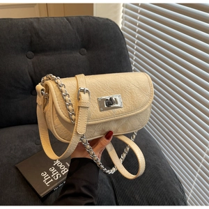 Detail of cream quilted mini chain bag featuring silver twist lock and leather texture