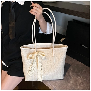 Détail du sac cabas en paille tissé avec un grand nœud en dentelle et fines bandoulières