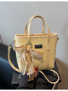 Fashionable beige woven bucket bag with lace bow accessory and cross-body strap