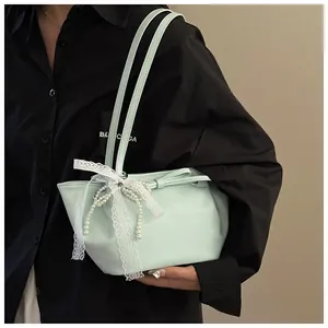 Détail du sac à épaule en cuir vert menthe avec nœud en dentelle et décor en perles