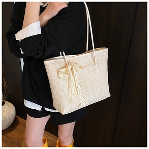 Détail du sac cabas beige tressé avec un nœud décoratif en dentelle et fines bandoulières