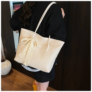 Détail du sac cabas tressé crème avec nœud en dentelle délicate et fines bandoulières