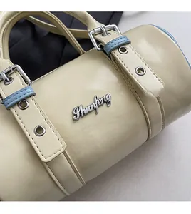 Macro shot of beige cylinder bag featuring silver Shuofeng logo and metallic buckle details
