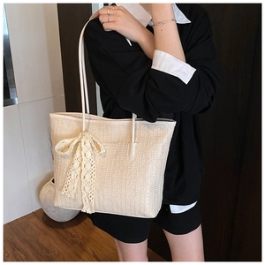 Détail du sac cabas en paille tressée avec nœud en dentelle et fine bandoulière en cuir