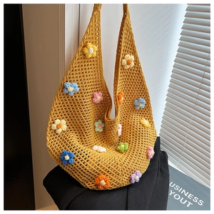Detail view of colorful handmade crochet flowers on a yellow woven hobo shoulder bag