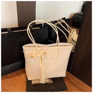 Gros plan du sac cabas beige tressé avec nœud en dentelle et fines bretelles en cuir