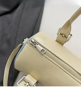 Detail of silver zipper and lychee texture on beige cylindrical handbag top